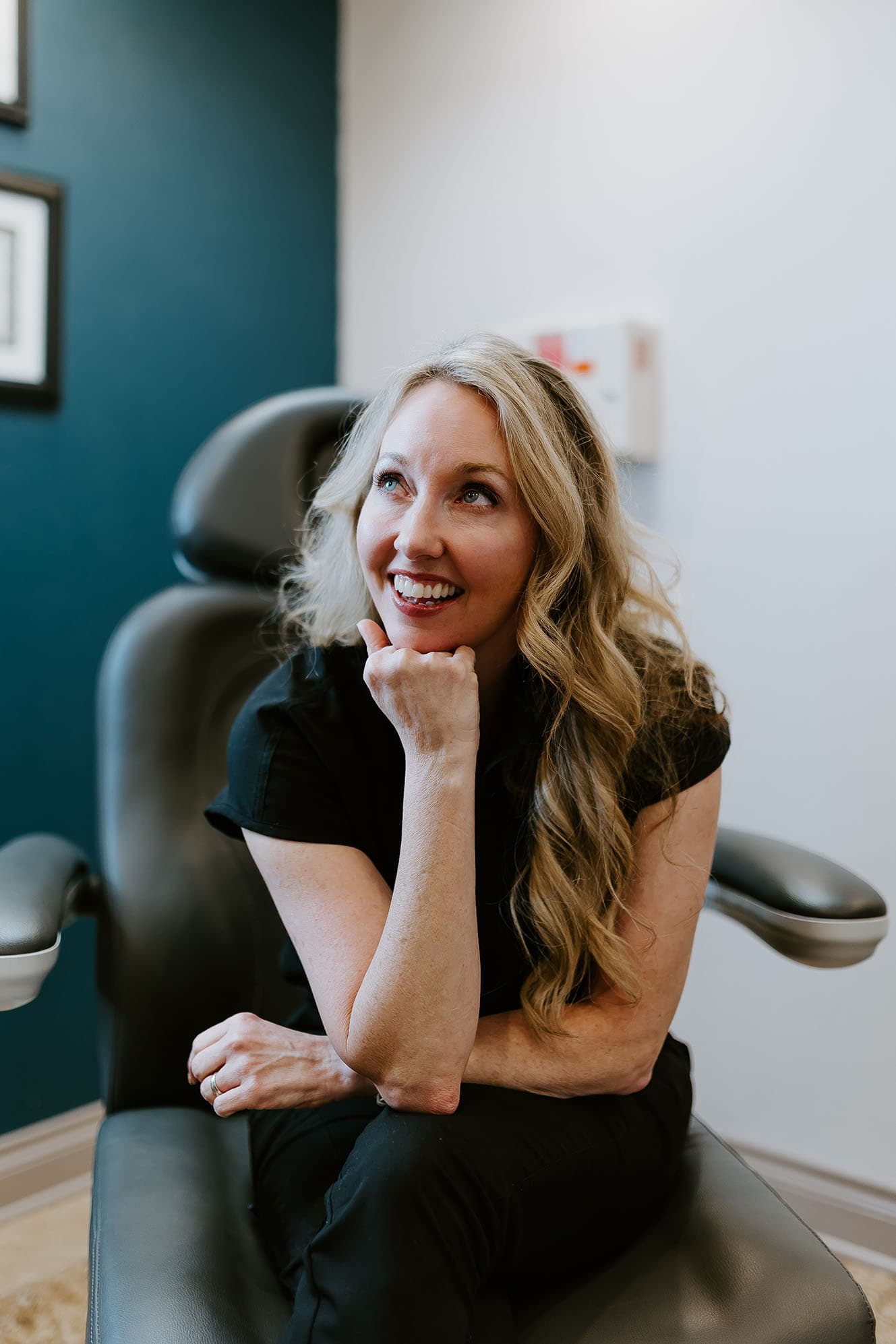 Dr Jen Upton sitting in her treatment chair gazing happily up