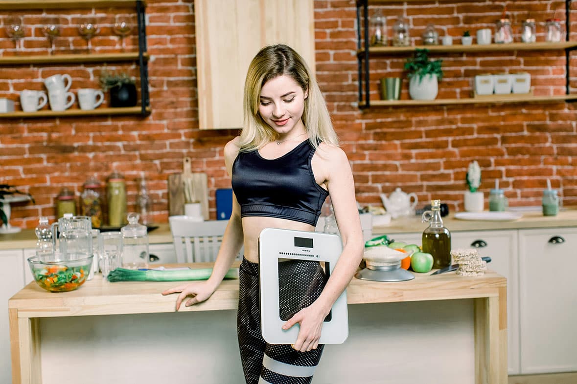 Person standing in the kitchen holding a scale